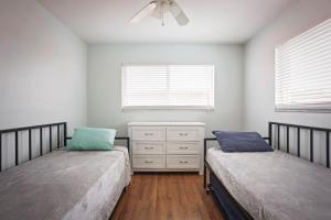 a bedroom with two beds and a dresser and two windows at Sun, Sand, Coastal Haven 3 in Clearwater Beach