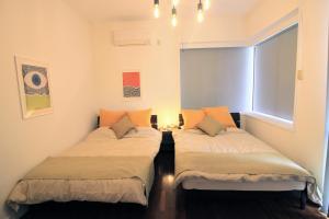 two beds in a small room with a window at Guest room MINAMI 沖縄 in Okinawa City