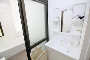 a white bathroom with a sink and a mirror at Guest room MINAMI 沖縄 in Okinawa City