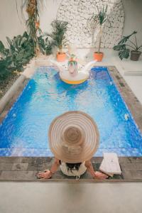 eine Person mit einem großen Hut in einem Schwimmbad in der Unterkunft Demoska Villa Jogja With Privatepool in Kejayan