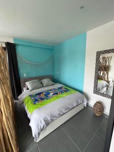 a bedroom with a bed with a blue wall at 2 accomodations -Studio du Manoir -Le Manoir in Punaauia