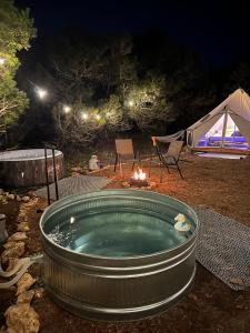 una bañera de hidromasaje por la noche con una tienda y una fogata en The Juniper Ranch and Retreat en Canyon Lake
