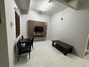 a living room with a table and a television and a table and chairs at Muhibbah Homestay in Sungai Siput