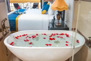 a bath tub with red flowers in it next to a bed at La Charm Hoi An Hotel - Peaceful Boutique In Old Town in Hoi An