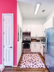uma cozinha com armários brancos e uma parede rosa em Dolly's Glam Getaway - Glittering Gem Near Broadway em Nashville