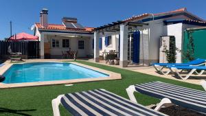 einen Pool mit zwei Stühlen und ein Haus in der Unterkunft Windy's Guest House in Aljezur