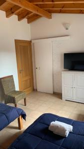 ein Schlafzimmer mit einem Bett, einem Stuhl und einem TV in der Unterkunft Windy's Guest House in Aljezur