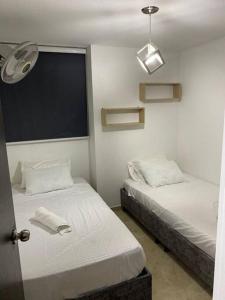 a bedroom with two beds and a window with a fan at Apartamento en Bucaramanga in Bucaramanga