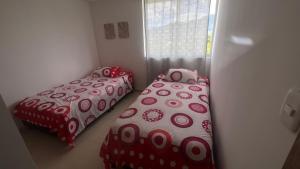 two beds in a room with red and white covers at Hermoso Apartamento en exclusiva zona ibague Calambeo in Ibagué