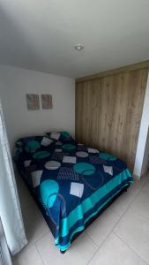 a bedroom with a bed with a blue comforter at Hermoso Apartamento en exclusiva zona ibague Calambeo in Ibagué