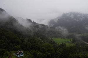 a misty mountain with a house on top of it at Drishtee Homestay in Rongli