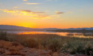 una puesta de sol sobre un cuerpo de agua con la puesta de sol en A Desert Oasis by the River, en Topock