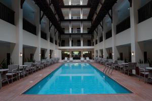 an indoor pool in a building with tables and chairs at Adelina Hotel and Suites in Mati