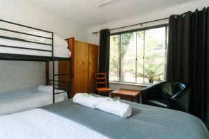 een slaapkamer met een stapelbed, een stoel en een raam bij Alpine Riverside Cottages in Porepunkah