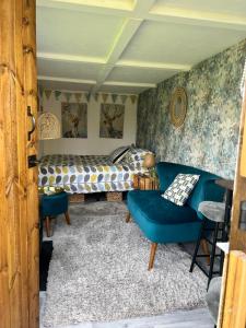 Bothy hut في ترينج: غرفة نوم بها أريكة زرقاء وسرير