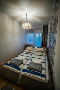 a bed in a bedroom with a chandelier at Főtér Apartman in Szarvas