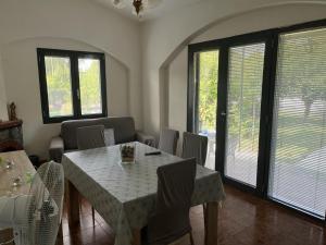 comedor con mesa, sillas y ventanas en Villa Maddy en Vibonati