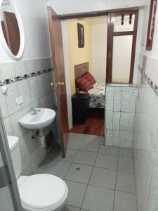 1 cama y baño con aseo y lavamanos. en Hospedaje Apu Salka, en Cusco