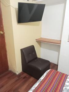 una silla negra en una habitación con TV en la pared en Hospedaje Apu Salka, en Cusco