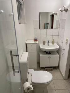 a white bathroom with a toilet and a sink at Comfortable apartment in commercial centre in Unterhaching