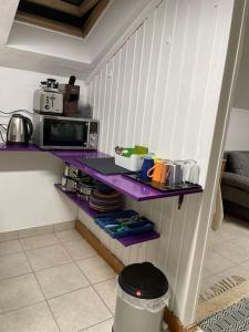 a kitchen with purple shelves and a microwave at Comfortable apartment in commercial centre in Unterhaching