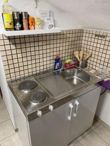 a small kitchen with a sink and a tiled wall at Comfortable apartment in commercial centre in Unterhaching