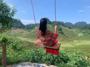 a woman sitting on a swing overlooking a valley at Mộc Châu Peachy Garden in An Pon