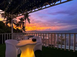 einen Tisch und Stühle auf einem Balkon mit Blick auf den Sonnenuntergang in der Unterkunft Lucky Tito PG Dive Resort in Puerto Galera