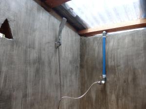 eine Dusche mit blauem Griff in einer Wand in der Unterkunft Magpie homestay in Bukit Lawang