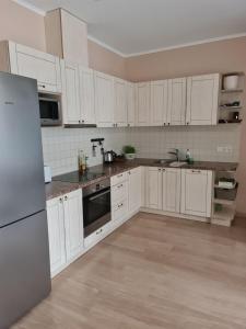 an empty kitchen with white cabinets and a refrigerator at Turaidas apartment Jurmala in Jūrmala