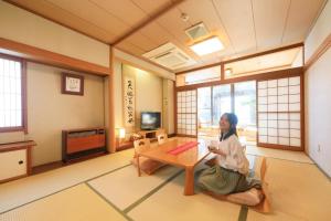 una mujer sentada en el suelo en una habitación en Hotel Pony Onsen, en Towada