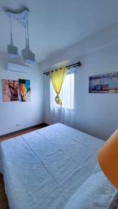 a white bedroom with a large bed with a window at Cozy almond drive condo in cebu in Talisay