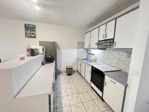 una cocina con encimeras blancas y armarios blancos en NEW My Lodge - AC, Netflix & Wifi, en Papeete
