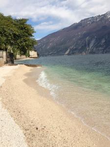 einen Strand mit Meer und Bergen im Hintergrund in der Unterkunft Hotel Locanda Ruscello Garnì in Limone sul Garda