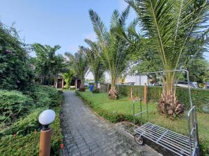 a garden with palm trees and a walkway at โรงแรม อมรอินน์ รีสอร์ท in Chiang Rai