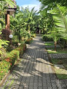 a cobblestone path in a garden with palm trees at โรงแรม อมรอินน์ รีสอร์ท in Chiang Rai