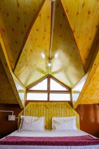 a bed in a room with a wooden ceiling at JOYstels Kasol in Kasol
