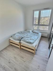 a bed sitting in a room with two windows at FREE 2X parking and free Wifi NEW Suncatcher apartment in Bratislava