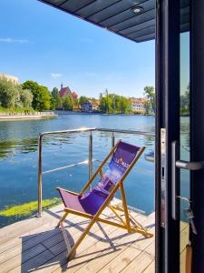 una silla púrpura sentada en un muelle junto al agua en Dom na wodzie LaMare XS 2 en Bydgoszcz
