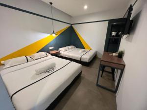a hotel room with two beds and a desk and a bed sidx sidx at Seeds Hotel Chow Kit in Kuala Lumpur