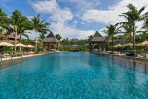 a pool at a resort with palm trees and umbrellas at The Ritz-Carlton Bali in Nusa Dua
