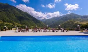 a swimming pool with chairs and mountains in the background at Dream Hotel in Haghpat