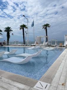 uma piscina com cadeiras brancas e palmeiras em Dreamland Oasis Apartment 614 em Chakvi