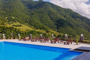 a pool with chairs and a mountain in the background at Dream Hotel in Haghpat