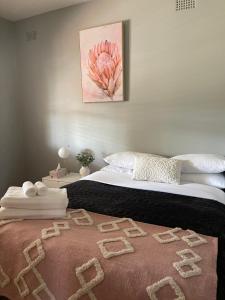 Un dormitorio con una cama con una flor rosa. en Charming & Cozy 2BR Cottage, en Blacktown