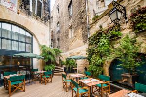 eine Außenterrasse mit Tischen und Stühlen sowie ein Gebäude in der Unterkunft Hotel Vatel Bordeaux in Bordeaux