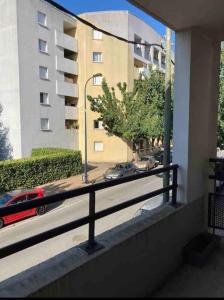 een balkon met uitzicht op een gebouw en een rode auto bij Beau 3 pièces cosy avec parking et terrasse in Bordeaux