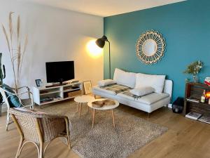 een woonkamer met een bank en een tv bij Beau 3 pièces cosy avec parking et terrasse in Bordeaux