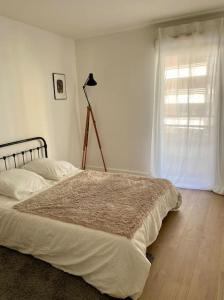 een witte slaapkamer met een bed en een raam bij Beau 3 pièces cosy avec parking et terrasse in Bordeaux