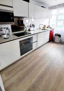 a kitchen with white cabinets and a wooden floor at Luxury 1 bed apartment-sea view in Bournemouth